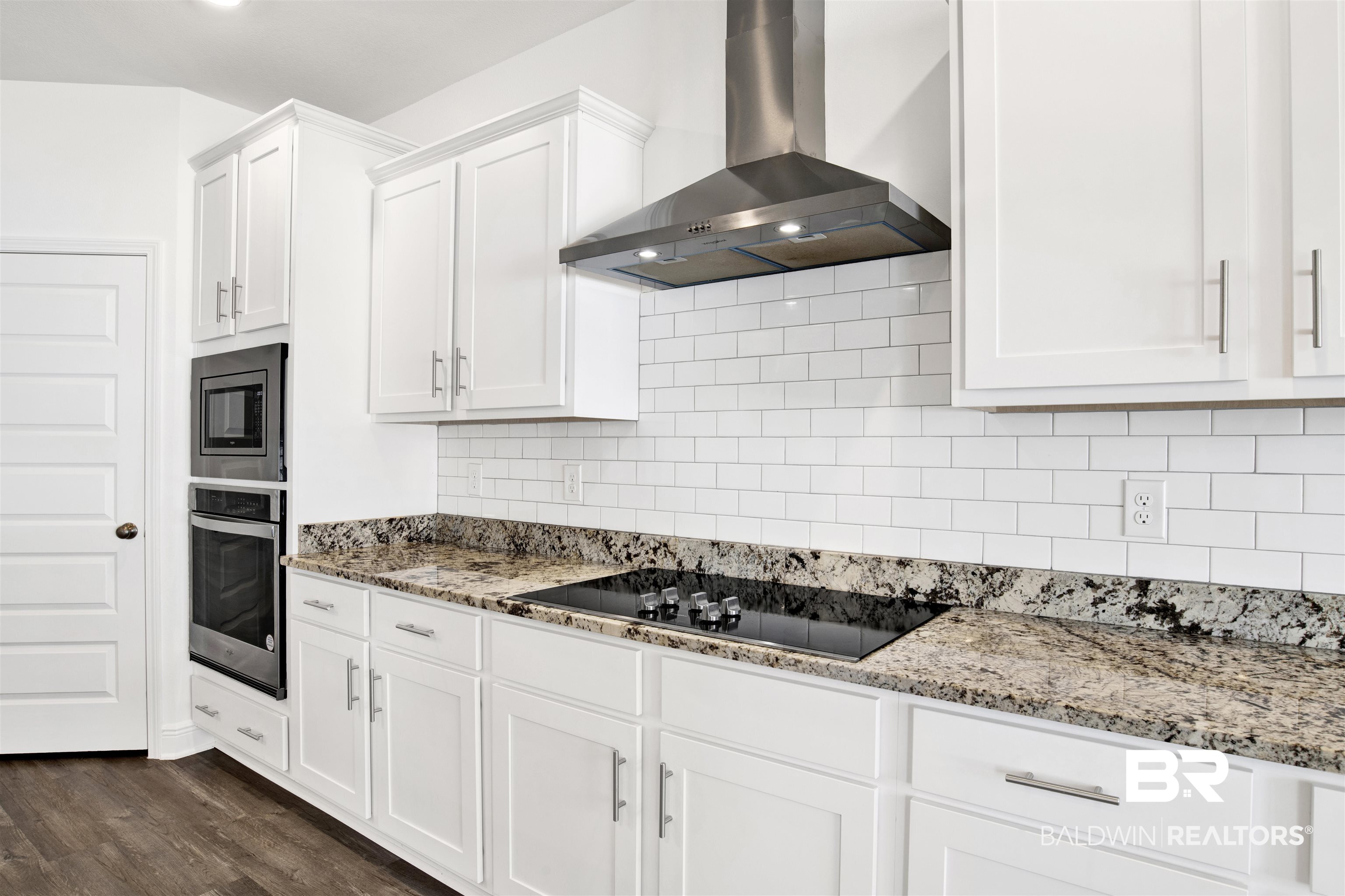 11602 Genuine Risk Circle Daphne, AL 36526 - Photo 12 of 30 Kitchen with wall chimney range hood, decorative backsplash, light stone countertops, white cabinetry, and stainless steel appliances