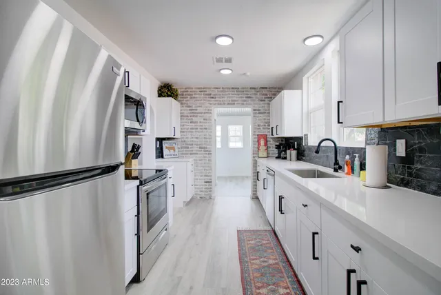 a kitchen with white cabinets and refrigerator