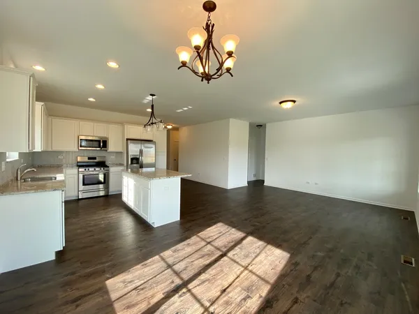 a kitchen with stainless steel appliances granite countertop a stove a sink dishwasher and a refrigerator with wooden floor