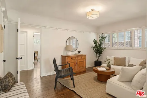 a living room with furniture a large window and wooden floor