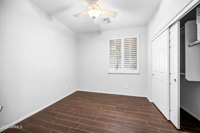 a view of empty room with wooden floor and fan