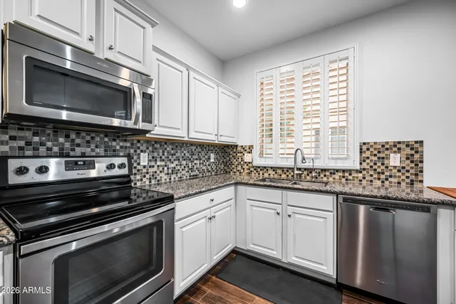 a kitchen with granite countertop a stove microwave and sink