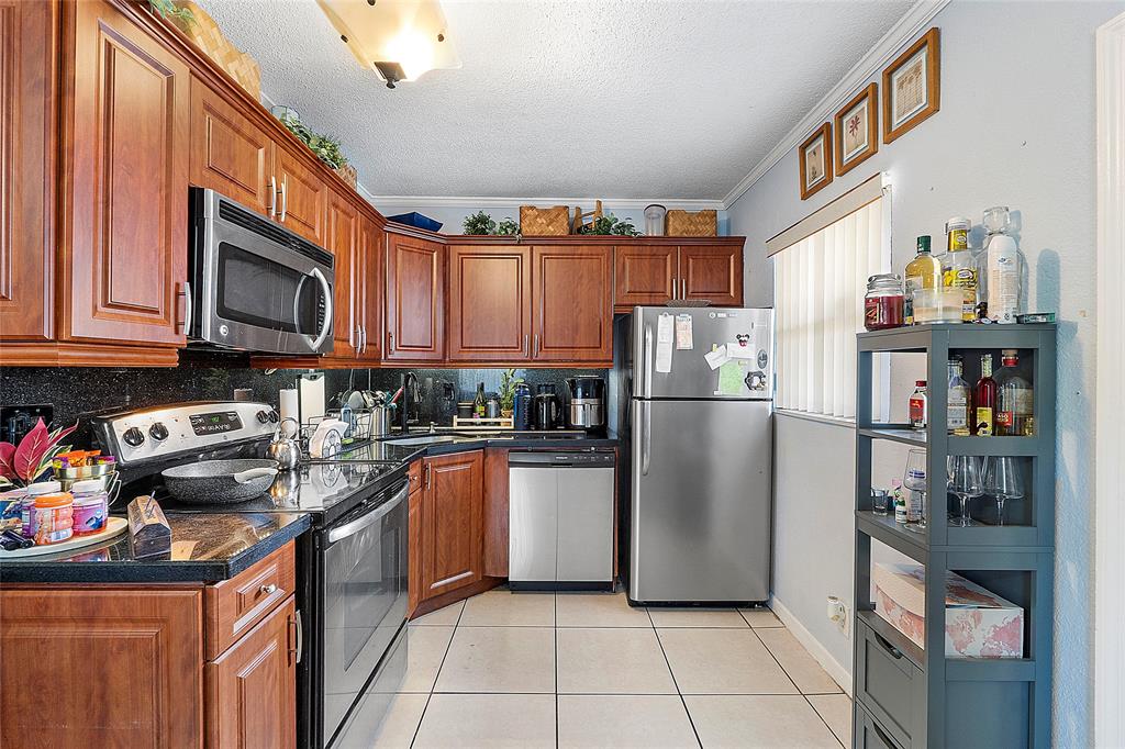 2741 Northeast 8th Avenue, Unit 10 Wilton Manors, FL 33334 - Photo 6 of 28 a kitchen with stainless steel appliances granite countertop a refrigerator and a stove top oven