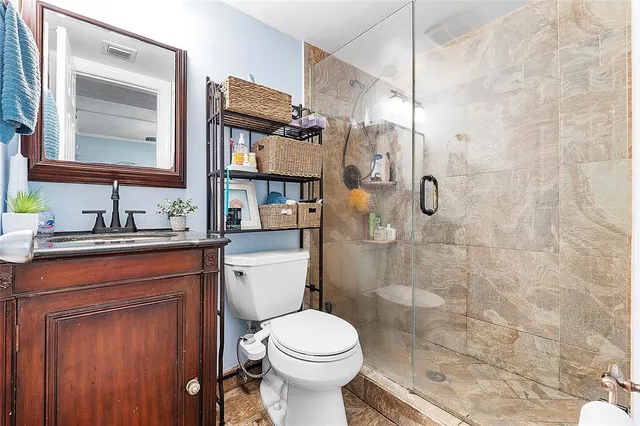a bathroom with a granite countertop toilet sink shower and mirror