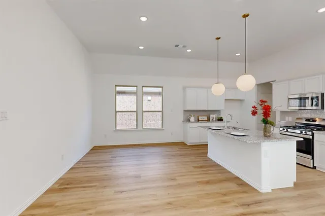 a kitchen with white cabinets and wooden floor