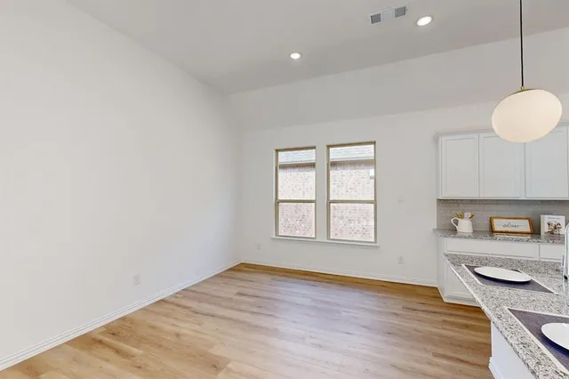 a view of a kitchen and an empty room with wooden floor and a window