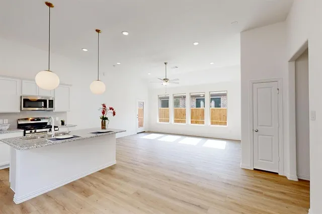 a view of a kitchen with kitchen island a counter top space stainless steel appliances and a ceiling fan
