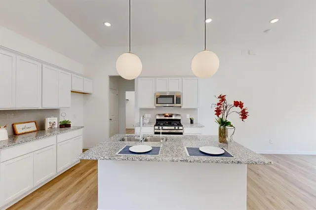 a kitchen with stainless steel appliances granite countertop a sink a stove and cabinets