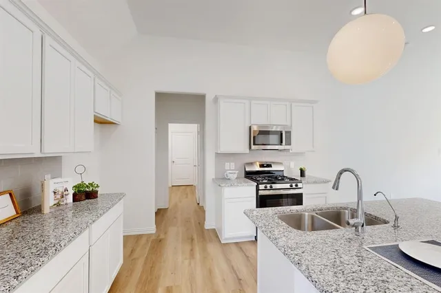 a kitchen with granite countertop a sink a counter space appliances and cabinets