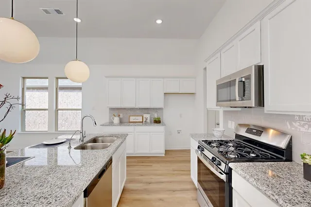 a kitchen with stainless steel appliances granite countertop a sink a stove and a wooden floors