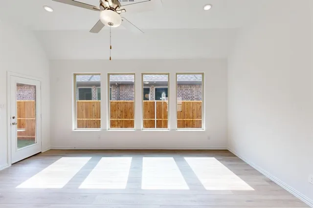 an empty room with windows and ceiling fan