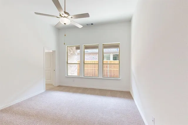 an empty room with chandelier fan and windows