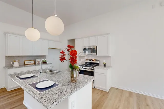 a kitchen with granite countertop a sink cabinets and wooden floor