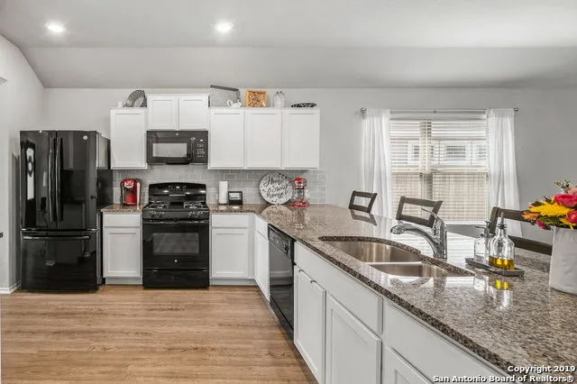a kitchen with stainless steel appliances granite countertop a sink a stove and refrigerator