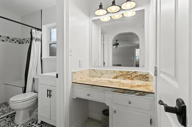 a bathroom with a granite countertop sink a toilet and a mirror