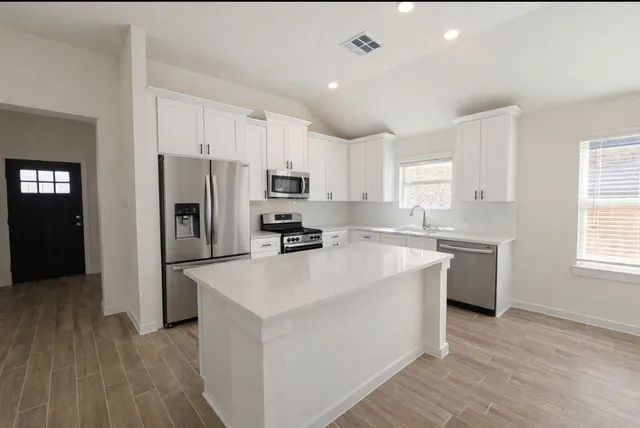 a kitchen with white cabinets and stainless steel appliances