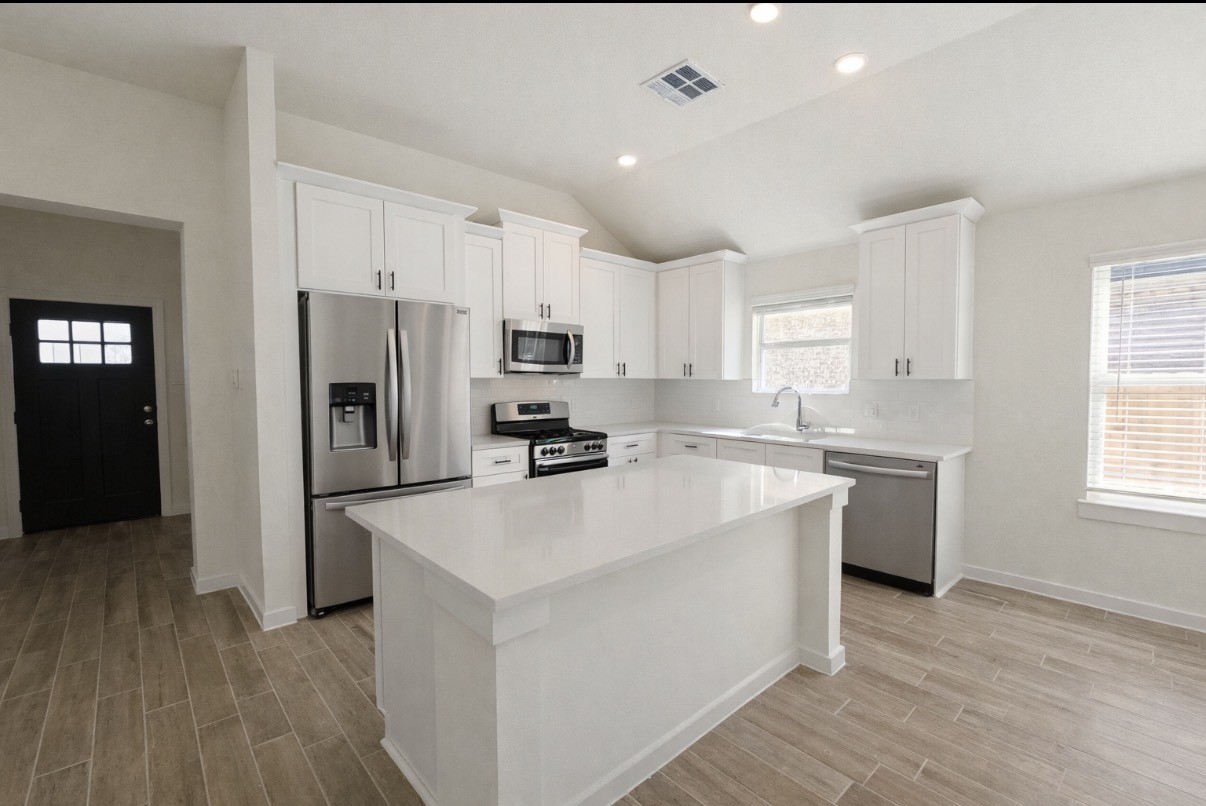 a kitchen with white cabinets and stainless steel appliances