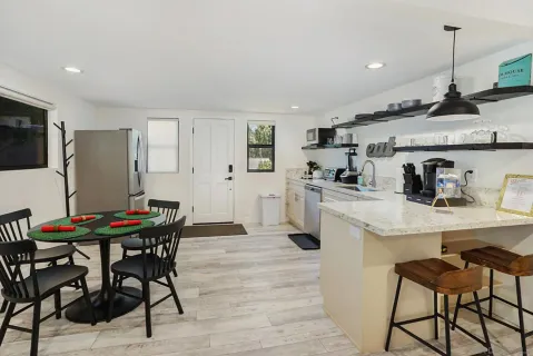 a kitchen with stainless steel appliances granite countertop a sink a stove a refrigerator and a dining table with wooden floor