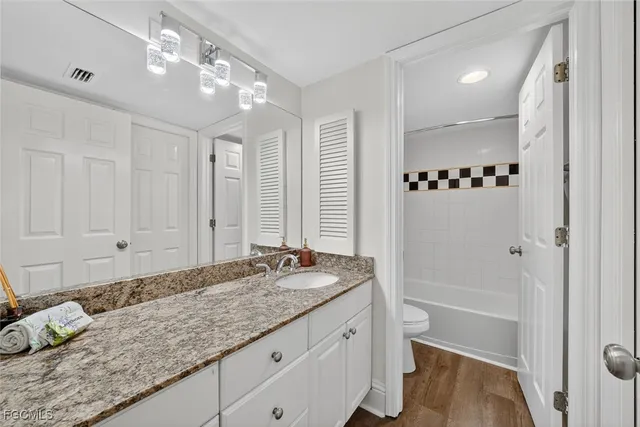 a bathroom with a granite countertop sink a mirror and a shower