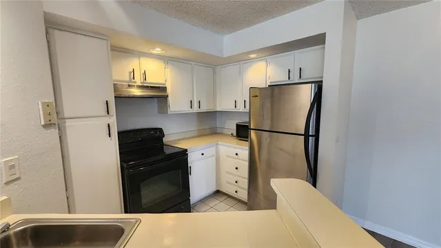 a kitchen with a refrigerator and white cabinets