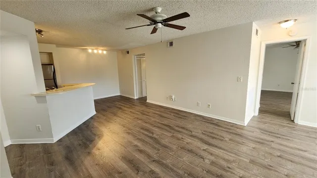 an empty room with wooden floor and a ceiling fan