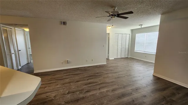 an empty room with wooden floor and a ceiling fan
