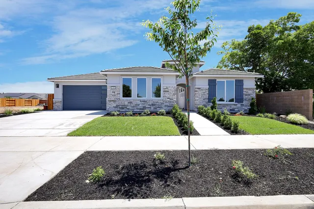 a house view with a garden space and a car parked in front of it