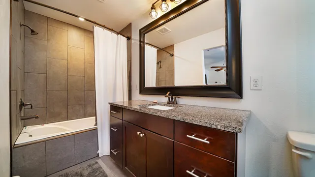 a bathroom with a granite countertop sink mirror and shower