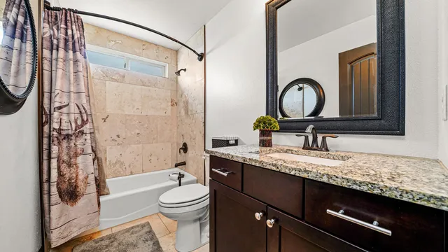 a bathroom with a granite countertop sink toilet a mirror a bathtub and shower