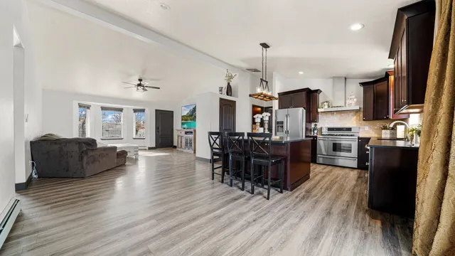 a living room with stainless steel appliances kitchen island granite countertop furniture wooden floor and a kitchen view