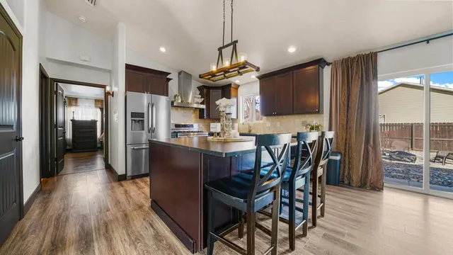 a kitchen with stainless steel appliances kitchen island granite countertop a refrigerator a stove a microwave oven a dining table and chairs with wooden floor