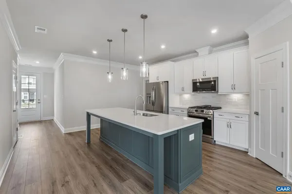 a kitchen with stainless steel appliances a sink a stove a refrigerator cabinets and wooden floor