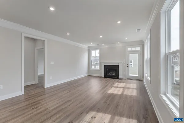 an empty room with wooden floor fireplace and windows