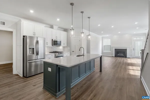 a kitchen with kitchen island a sink stainless steel appliances and wooden floor