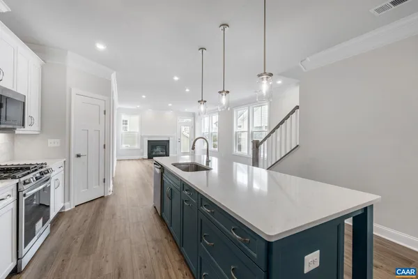 a kitchen with a stove a sink a center island and wooden floor