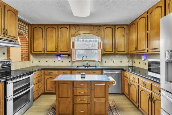 a kitchen with stainless steel appliances granite countertop a sink dishwasher stove and cabinets with wooden floor
