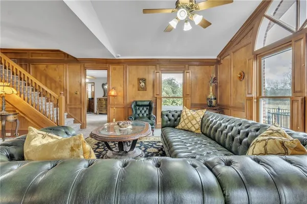 a living room with a bed a chandelier and a large window