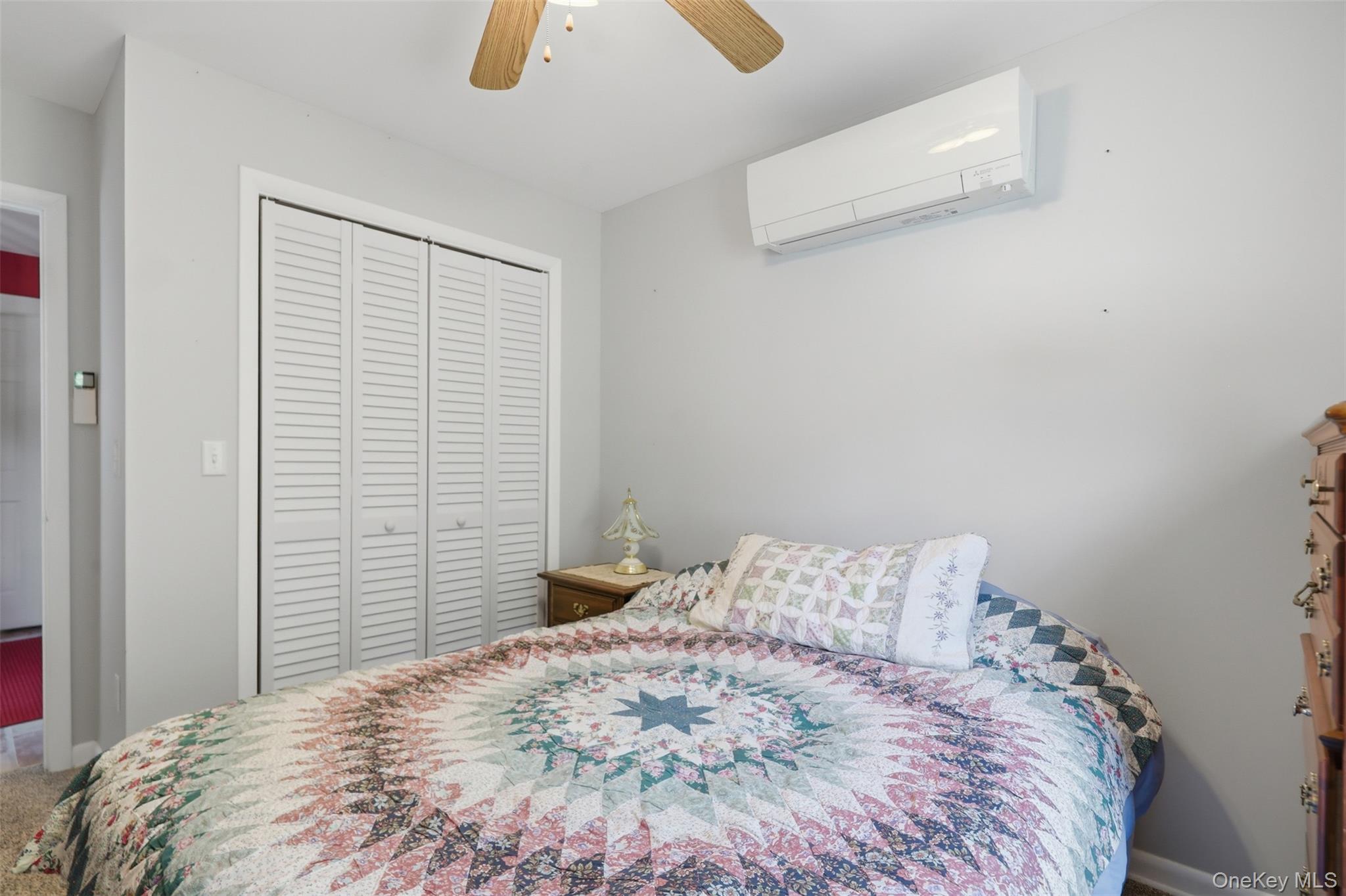 1 Hiko Place Fishkill, NY 12524 - Photo 19 of 41 Bedroom featuring a ceiling fan, wall-mounted climate control unit, and louvered bifold closet doors