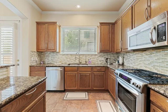 a large kitchen with stainless steel appliances granite countertop a stove and a sink