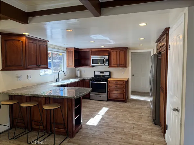 a kitchen with stainless steel appliances granite countertop wooden cabinets a refrigerator a stove a sink and a oven
