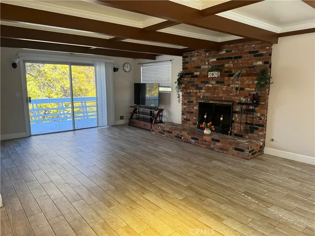 a view of an empty room with wooden floor fire place