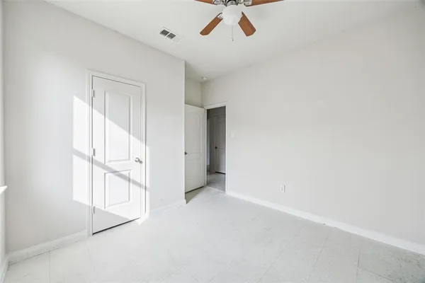 an empty room with a window and ceiling fan