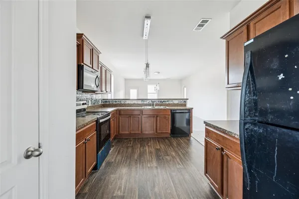 a kitchen with stainless steel appliances kitchen island granite countertop a stove a sink and a refrigerator