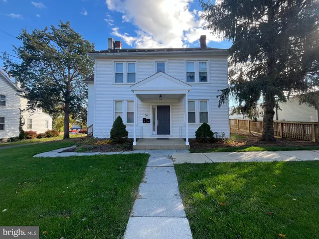 a front view of a house with a yard and trees