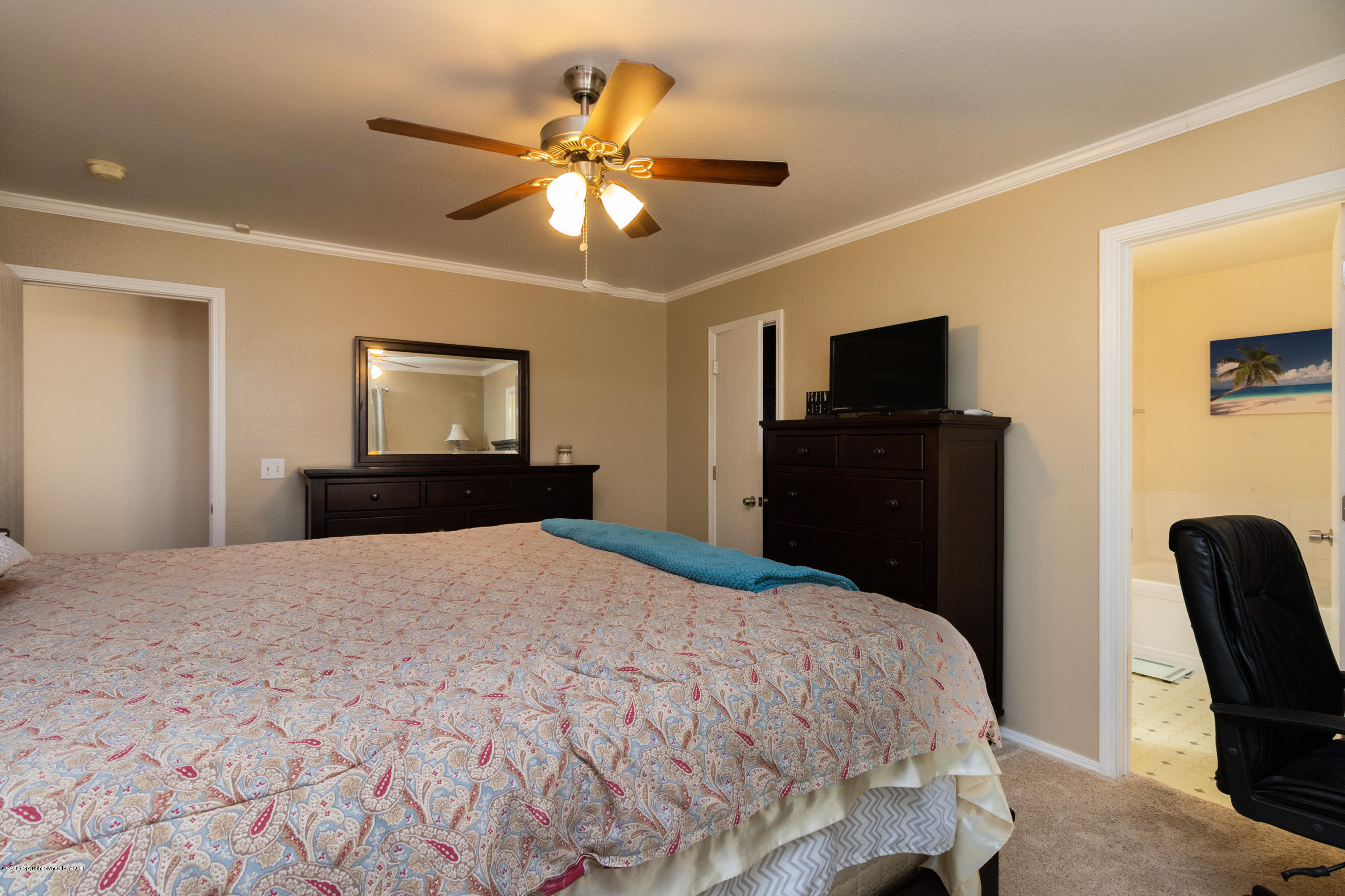 5203 Capulin Lane Amarillo, TX 79110 - Photo 17 of 29 a bedroom with a bed and a flat tv screen on dresser