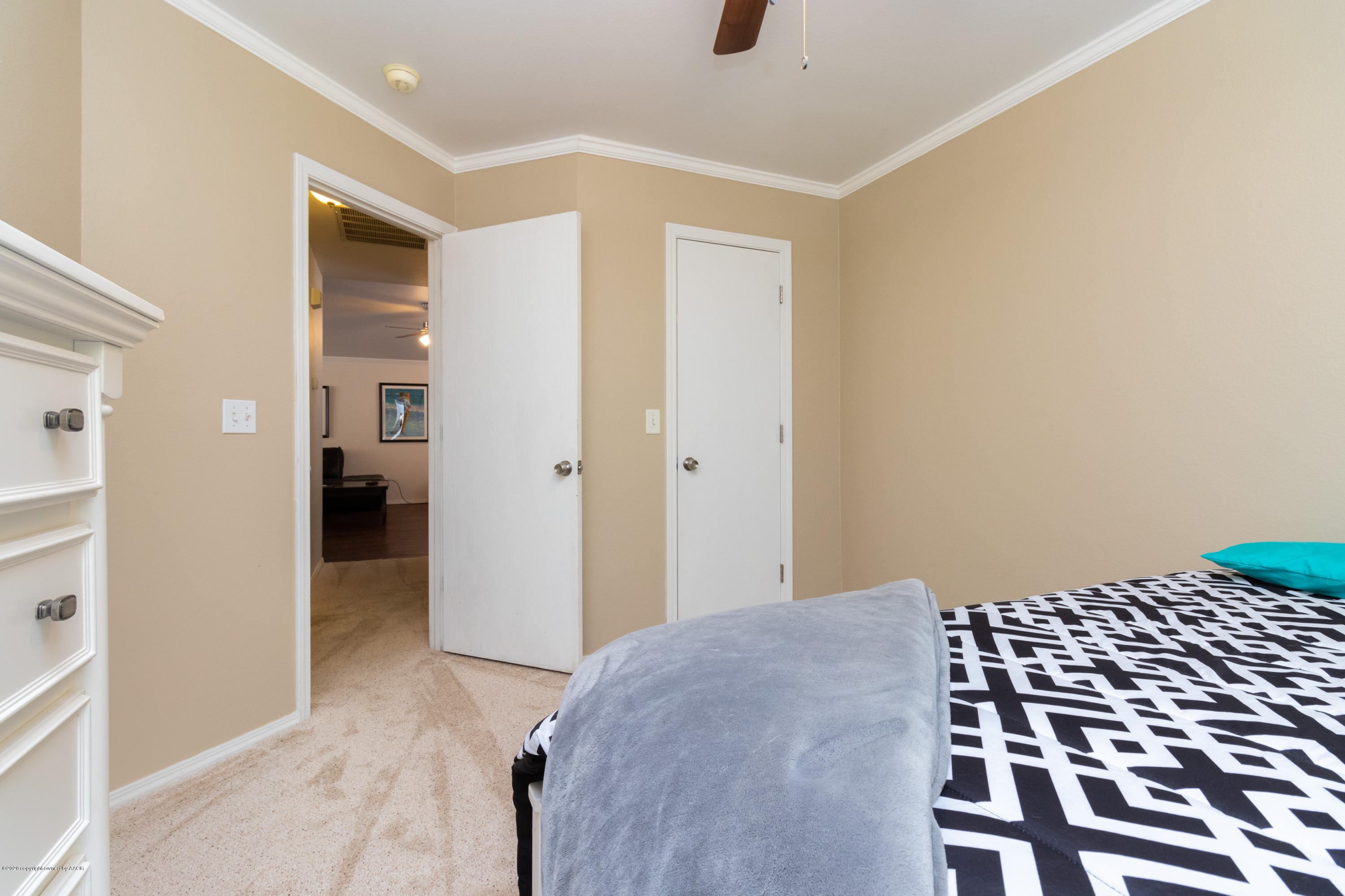 5203 Capulin Lane Amarillo, TX 79110 - Photo 26 of 29 a bedroom with a bed and a black walk in closet with wooden floor