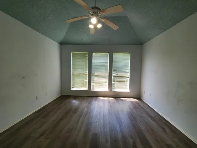 an empty room with wooden floor and windows