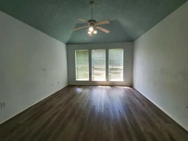 an empty room with wooden floor and windows