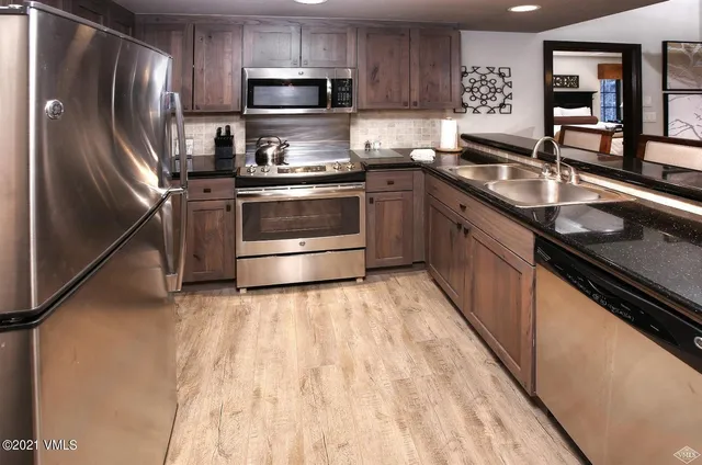 a kitchen with stainless steel appliances granite countertop a sink stove microwave and refrigerator
