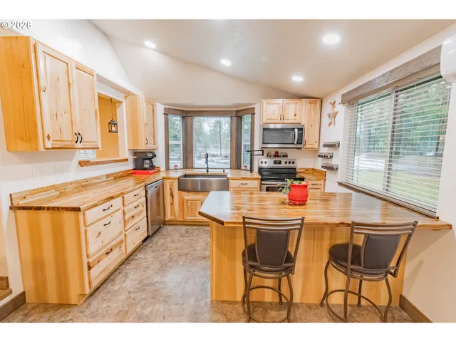 a kitchen with stainless steel appliances kitchen island granite countertop a stove a sink a dining table and chairs